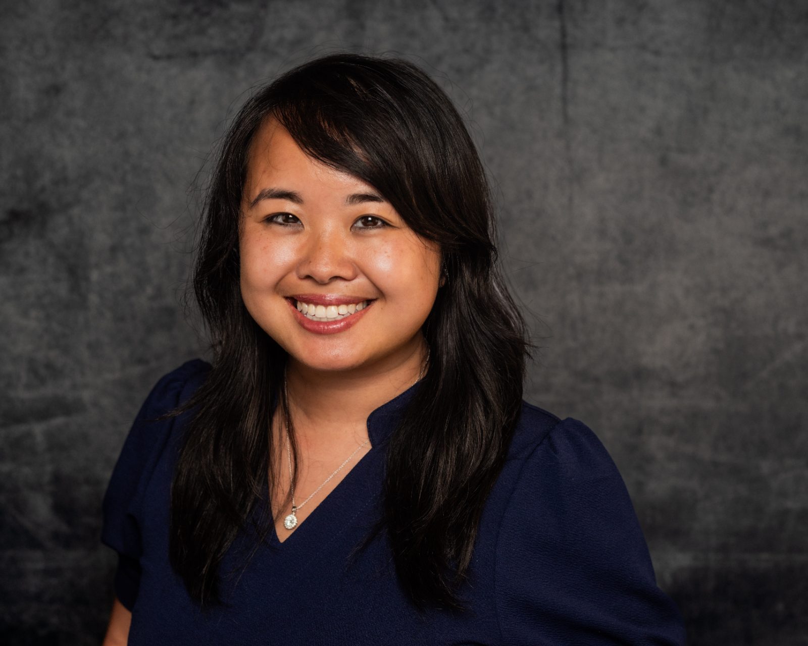 Portrait of Erica C. Chen smiling in a navy dress