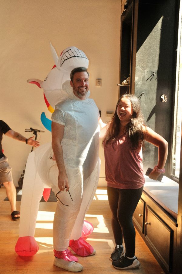 Two participants laughing, one in a unicorn costume