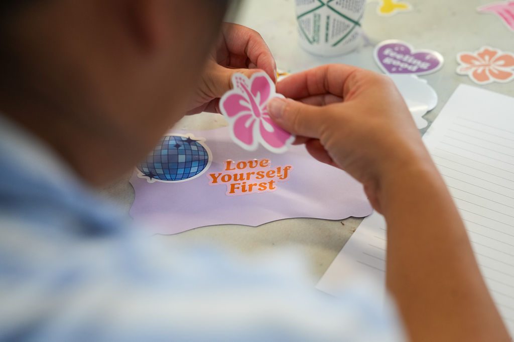 Choosing a sticker for a board that reads Love Yourself First
