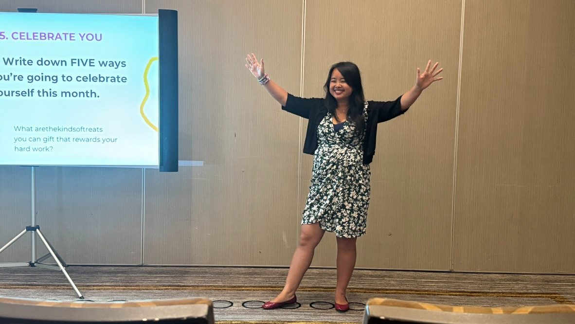 Erica C. Chen on stage with arms wide open during a keynote